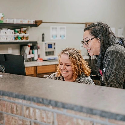 Veterinary staff members smiling and assisting clients at the animal clinic reception desk