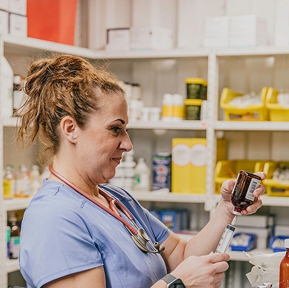 Veterinary team member preparing medication inside an animal clinic treatment area